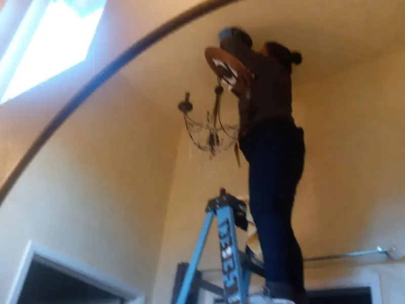 Electrician installing a chandelier in a Manning residence